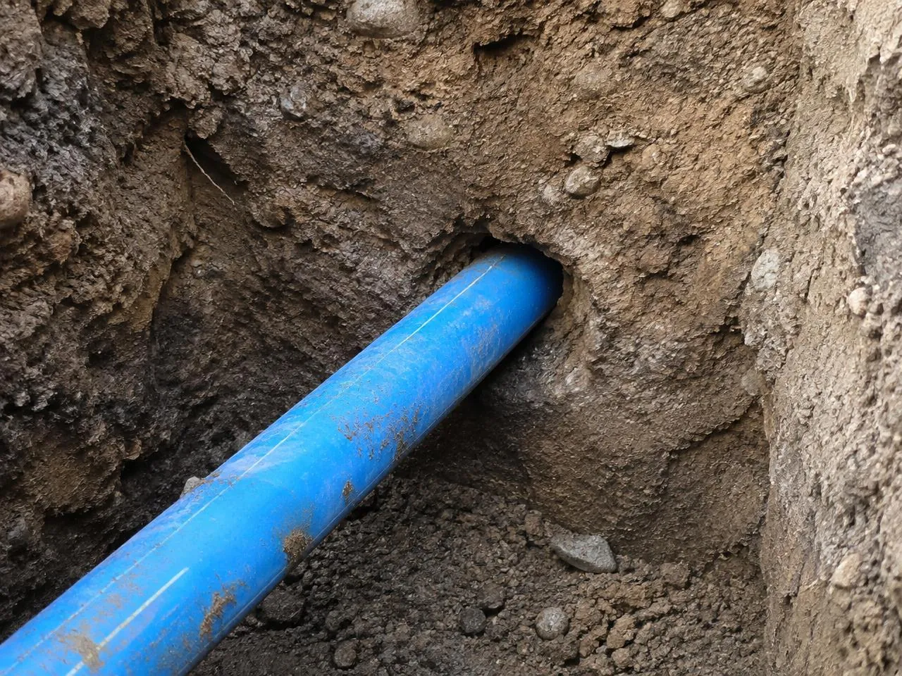 Blue water pipe emerging from an underground bore into a reception pit